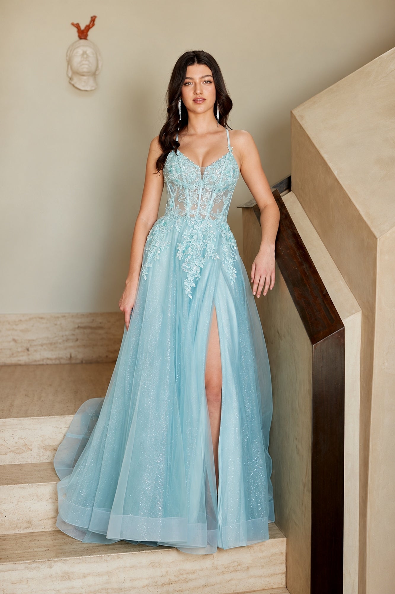 A light blue, floor-length Long Prom Dress: Amelia Couture 4074 featuring a sheer bodice, lace appliqués, and a high side slit.